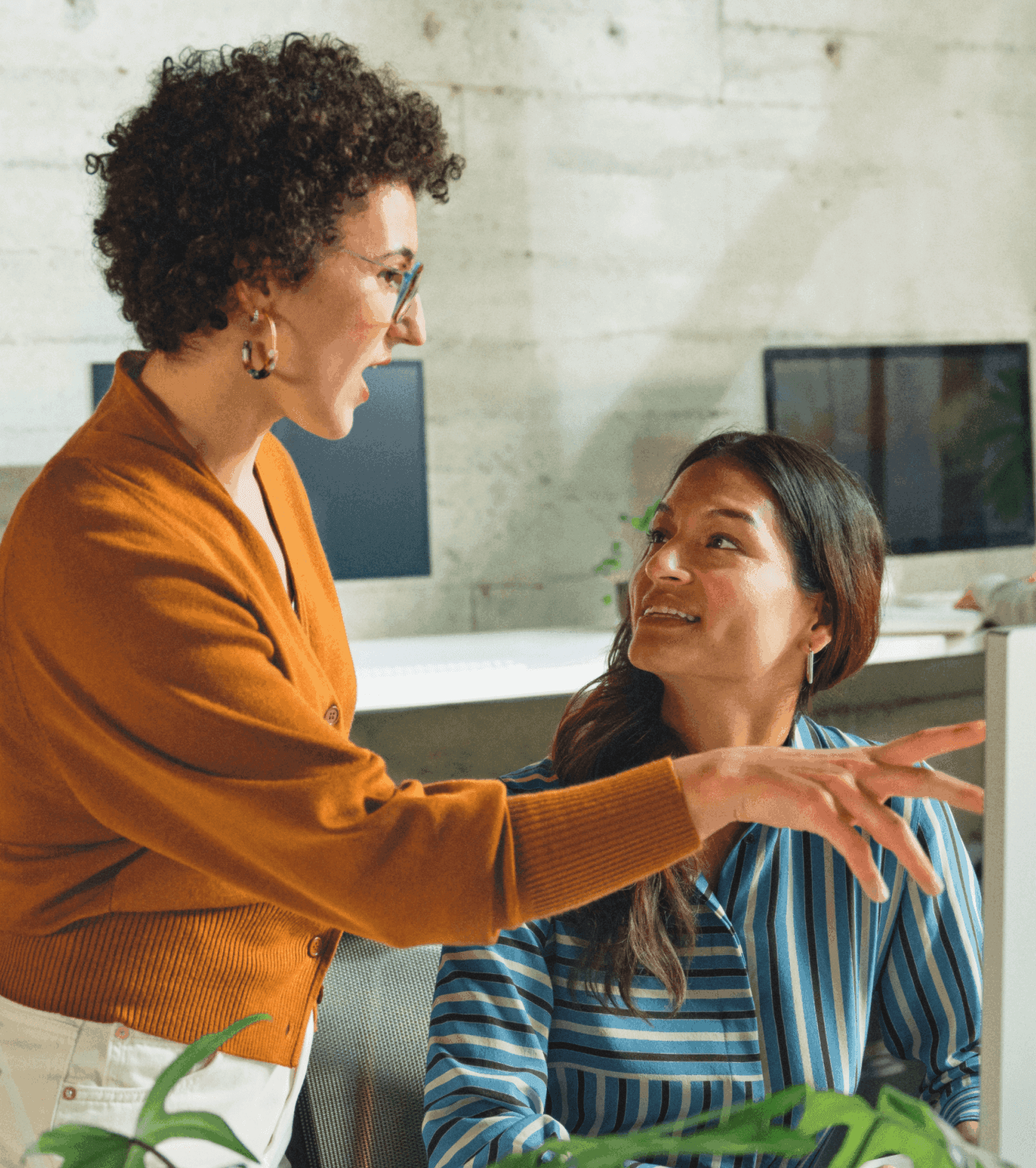 Photo of female coworkers talking in front of desktop computer