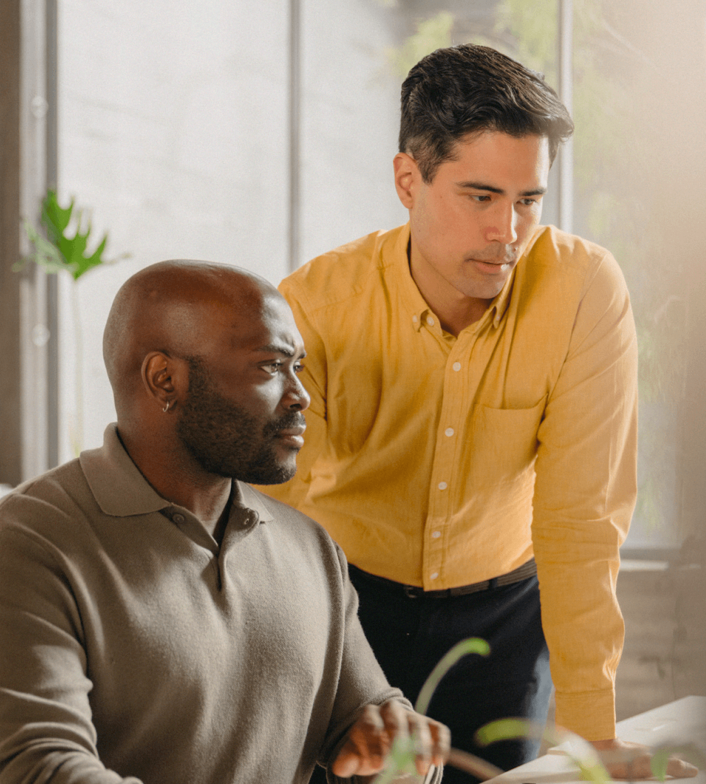 Two coworkers reviewing content on a computer in warmly lit office
